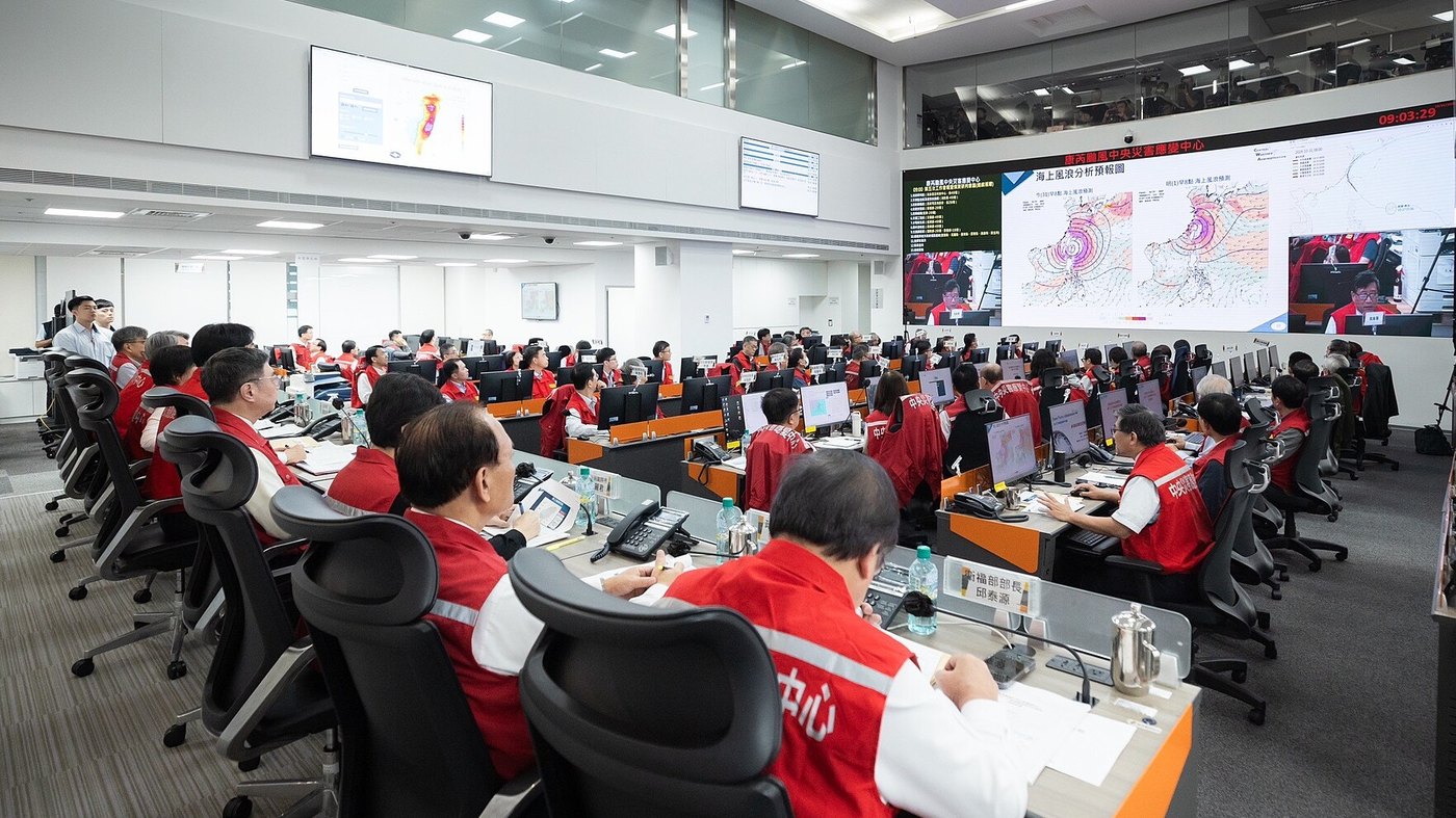 An operations centre with rows of operators at workstations facing a wall of monitoring screens