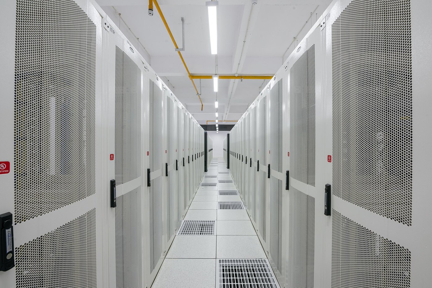 A data centre aisle with two rows of white server cabinets facing each other