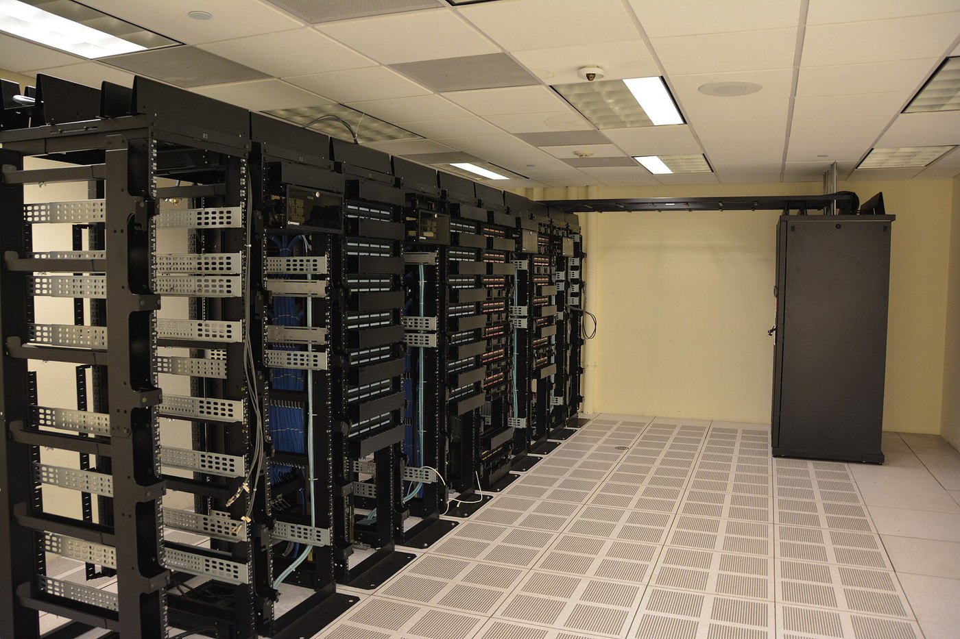 An open frame network rack with cable management brackets and a raised floor with perforated vent tiles
